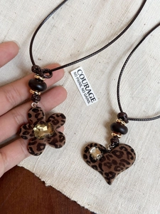 Detailed close-up of leopard print heart and flower resin pendants with rhinestones
