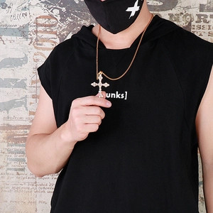 Pendentif croix en or hip-hop avec zircons sur un mannequin devant un mur rétro