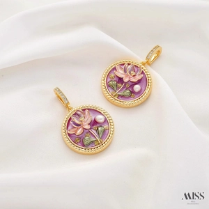 Detail of floral enamel charms with pink lotus and white pearl on white satin fabric