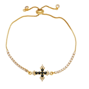Detail view of a gold cross bracelet with black and white zircon and a slider clasp