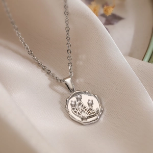 Silver butterfly coin pendant necklace on beige silk fabric with soft lighting