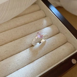 Macro shot of silver open ring with pink oval stone and star embossing in jewelry box