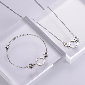 Macro shot of silver zircon jewelry set with clover pendants on acrylic display stand