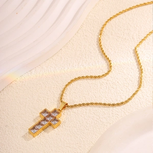 Macro shot of gold cross pendant necklace featuring square cubic zirconia stones