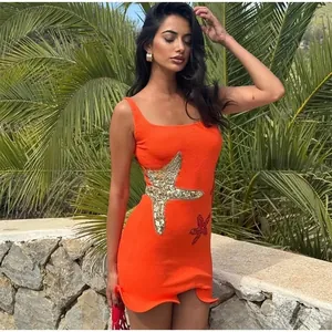 Detailed close-up of orange mini dress with gold sequin starfish embroidery and texture