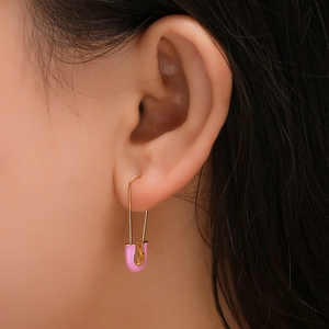 Y2K style pink enamel safety pin earrings in gold finish worn by a model