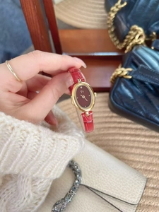 Detail of red leather strap watch with gold oval case worn on wrist for an elegant look