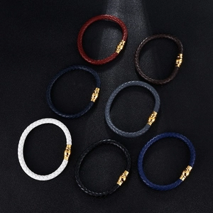 Braided leather bracelets in seven vibrant colors with magnetic gold buckles on a dark surface