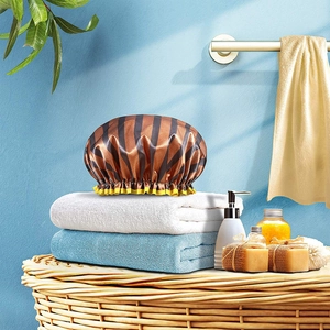 Brown striped waterproof shower cap with yellow ruffles on a towel in a bathroom setting