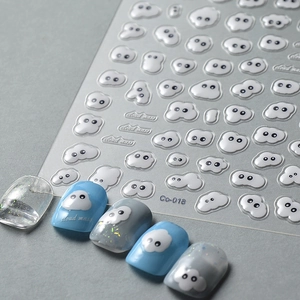 Macro detail showing 3D embossed white cloud nail stickers with textured matte finish