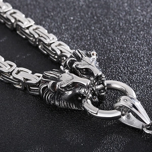Close-up of a masculine silver steel necklace featuring detailed lion head shield clasps