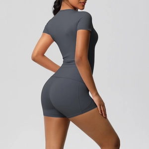 Back view of a woman in a dark grey short-sleeve yoga top and matching biker shorts set