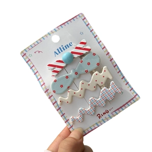 Lot de quatre barrettes en acrylique colorées à rayures et pois sur carte support