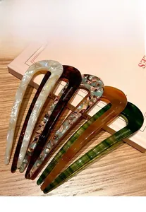 Detail view of 5-piece acetate U-shaped hair pins with marbled textures on a book