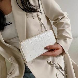 Close-up of white crocodile pattern wallet with gold zipper and metal chain strap