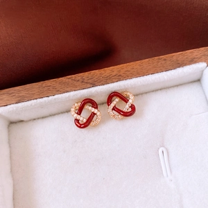Detail shot of interlocking gold earrings with red enamel and pavé rhinestones
