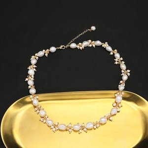 Macro view of baroque pearl necklace with gold accents on an elegant vintage metal tray