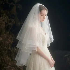 Detail of white multi-layer short bridal veil with fluffy soft tulle layers and hair comb
