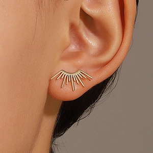 Vue détaillée de boucles d'oreilles soleil dorées aux lignes ajourées sur un modèle