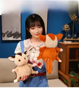 Close-up of soft plush sugar glider toys in brown and orange held by a hand