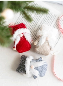Three wool felt Christmas gnomes decorations with white beards on a festive background