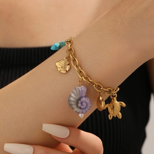 Detail of gold chain bracelet with colorful sea charms like turtle and shell on wrist