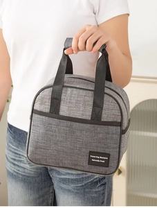 Gray insulated lunch bag with reinforced handles shown in a lifestyle setting