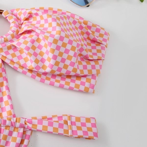 Detailed macro of pink and orange checkered bikini top with ruffled texture and tie detail