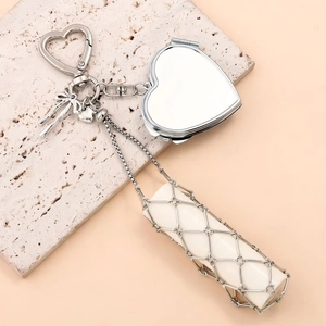 Detailed view of silver heart-shaped mirror and metal mesh lipstick holder on stone base