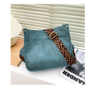 Detail of dark green crossbody bag featuring a stylish leopard print wide strap and gold hardware