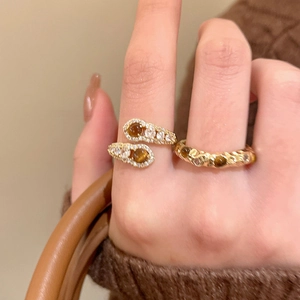 Close-up of gold-plated tiger eye stone rings on a hand with warm autumn vibe background