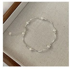 Detailed view of S925 silver curved tube bracelet with pearls and a heart charm