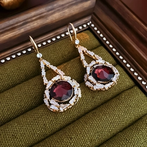 Detail of vintage ruby red crystal drop earrings with gold frame on green velvet