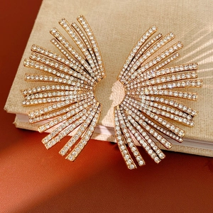 Detailed view of geometric fan-shaped earrings with sparkling rhinestones on fabric