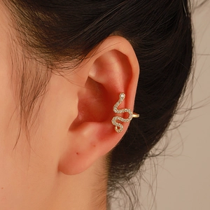 Vista macro di un earcuff a serpente dorato con diamanti brillanti sull'orecchio