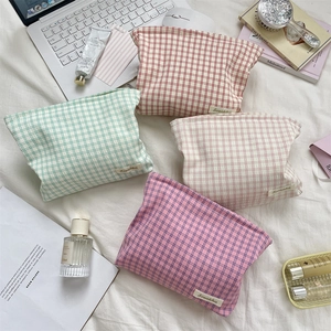 Close-up of four grid pattern fabric cosmetic bags in pastel colors on a white fabric surface