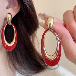 Detailed close-up of retro red enamel oval earrings with gold metal and stud detail