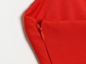 Macro du tissu rouge de la robe montrant la fermeture éclair invisible et sans couture