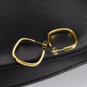 Macro view of 18K gold plated square hoop earrings on premium black textured leather