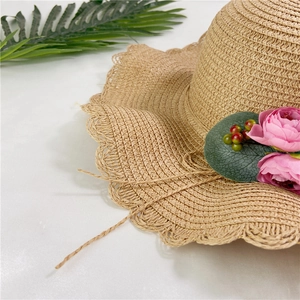 Détail d'un chapeau de paille orné d'une fleur élégante et d'un bord ondulé chic