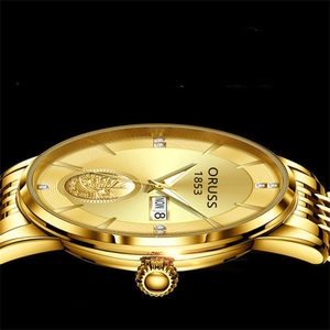 Macro shot of gold quartz watch with double calendar display and sailboat relief