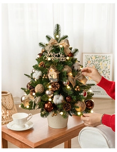 Mini tabletop Christmas tree with LED lights and festive ornaments on a cozy desk