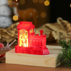Macro shot of red Christmas locomotive lamp featuring Santa and reindeer on wood base