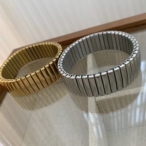 Vue macro de bracelets extensibles en acier doré et argenté sur une table en verre
