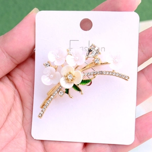 Close-up of vintage floral brooch with white shell petals and green enamel leaves