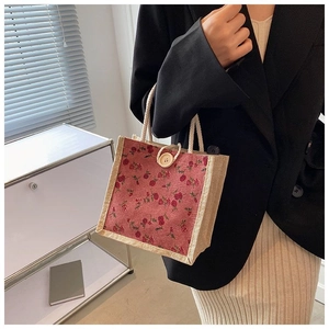 Mini floral tote bag with red rose pattern and beige linen handles held by a model