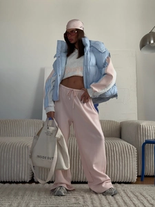 Detail of a casual sportswear set featuring light blue vest and pink jogger pants on model