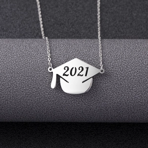 Macro shot of silver graduation cap pendant with 2021 engraving on textured background