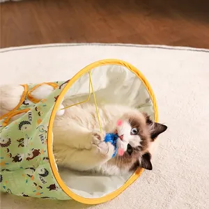 Green patterned cat tunnel toy with hanging blue feather pompom for indoor play