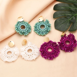Three pairs of handmade bohemian beaded hoop earrings in green, white, and fuchsia colors